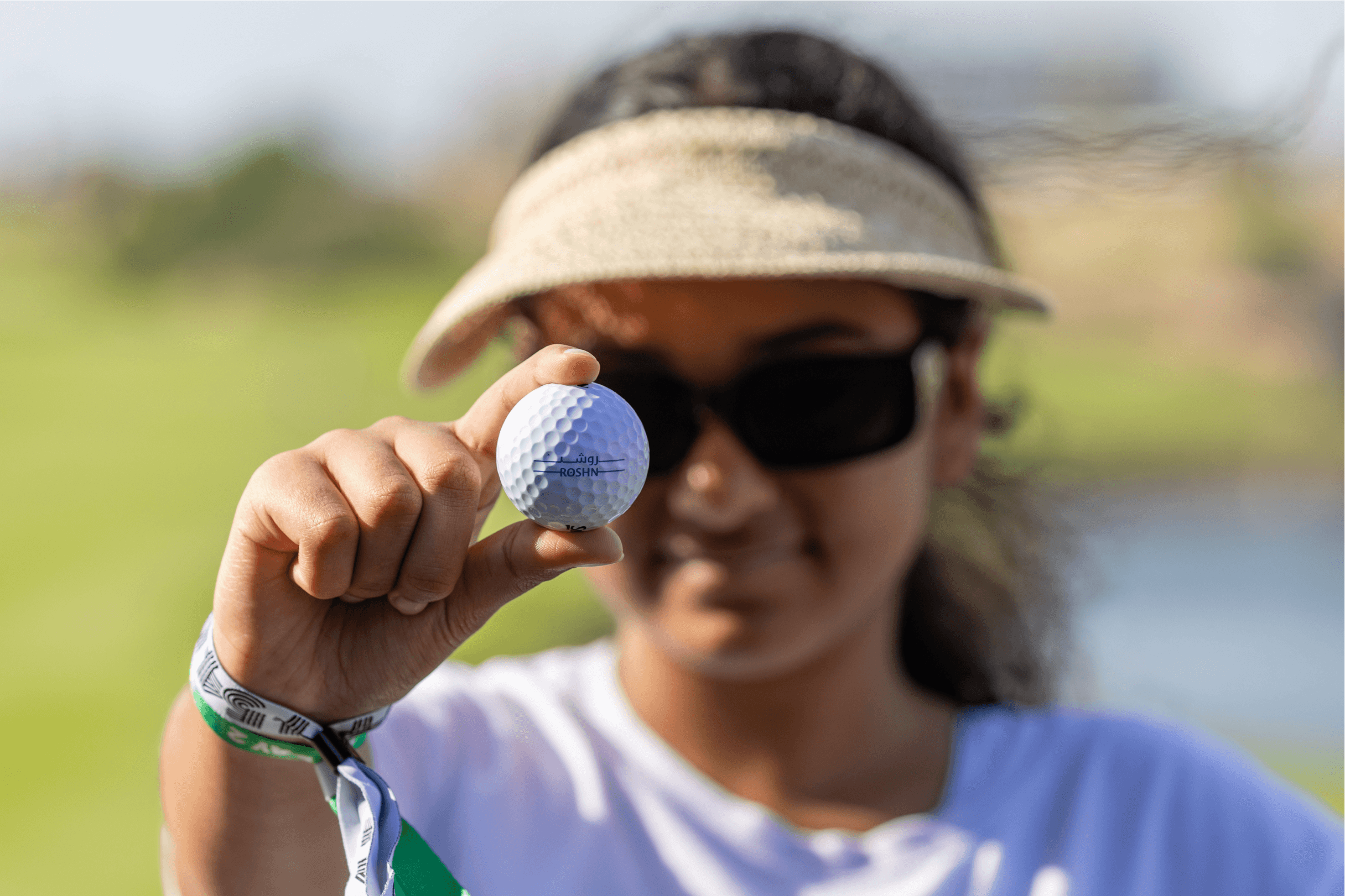 Women holding a golf ball, symbolizing ROSHN Group's empowerment of women and community engagement